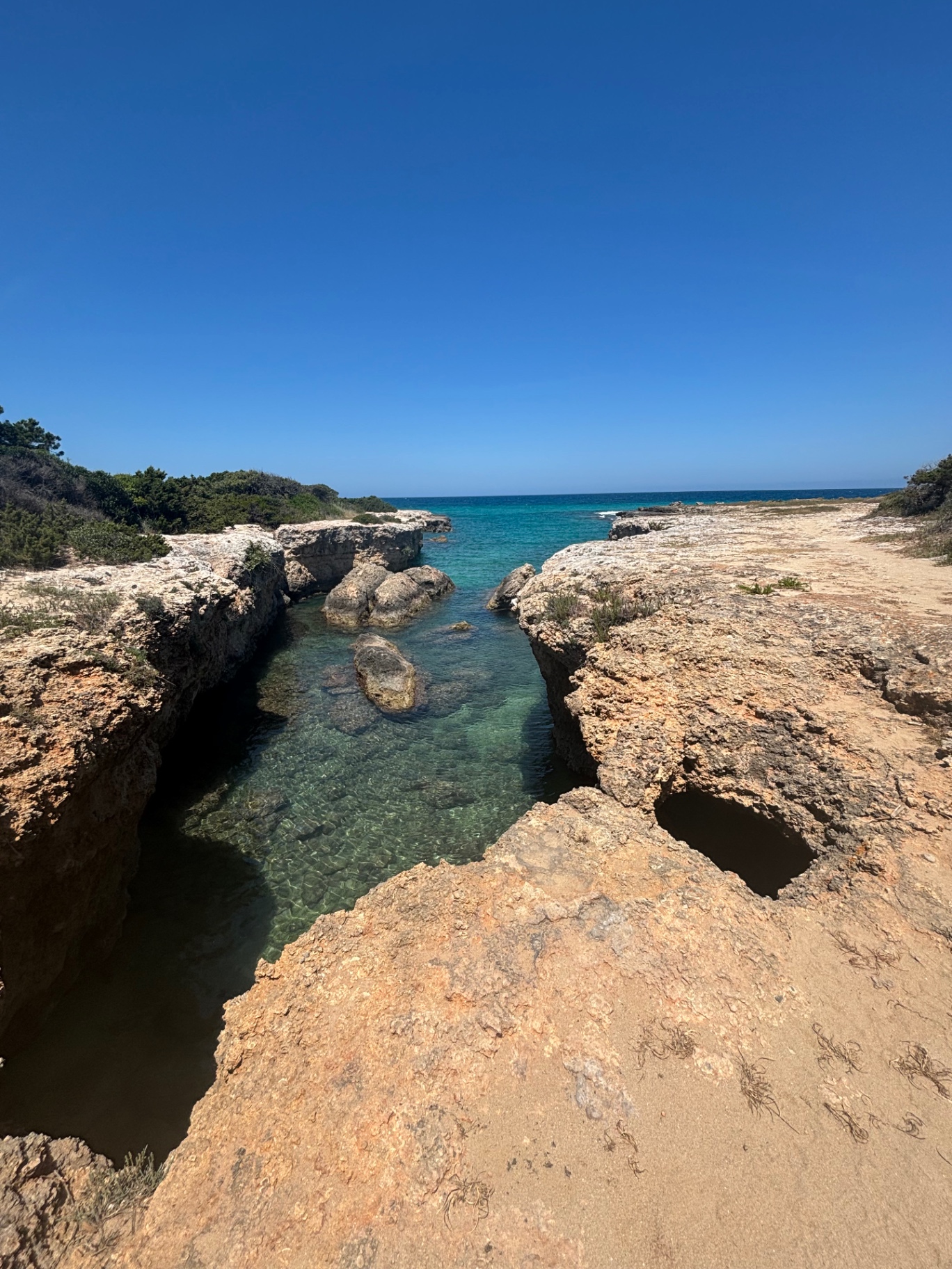 A turquoise swimming cove between limestone rocks on the Puglian coast